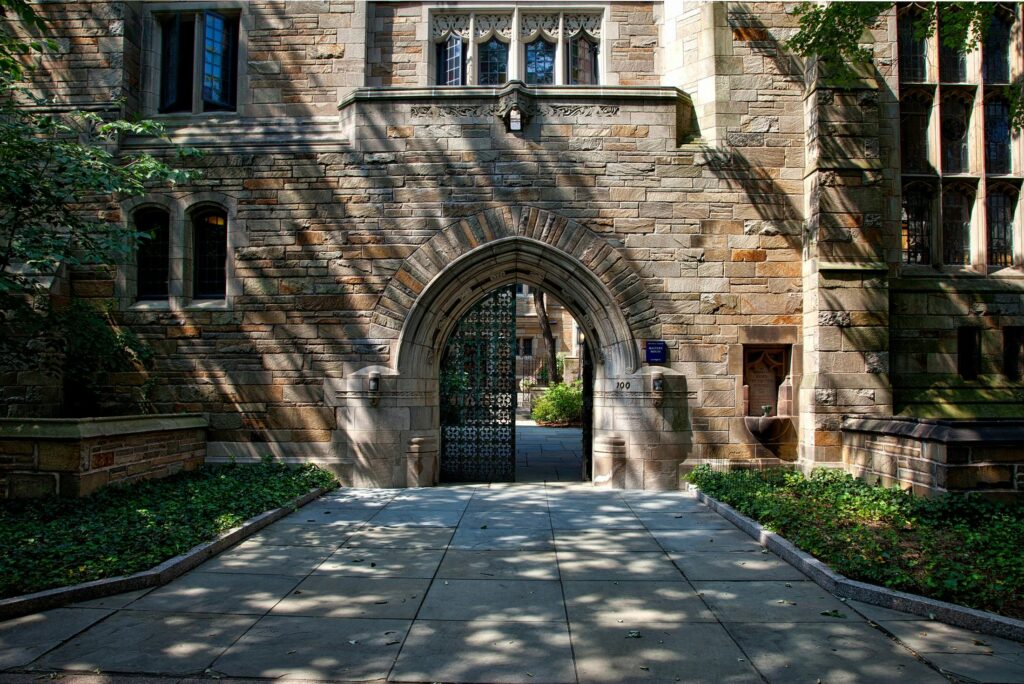 Gothic-style stone archway entrance at Yale University campus, surrounded by greenery.